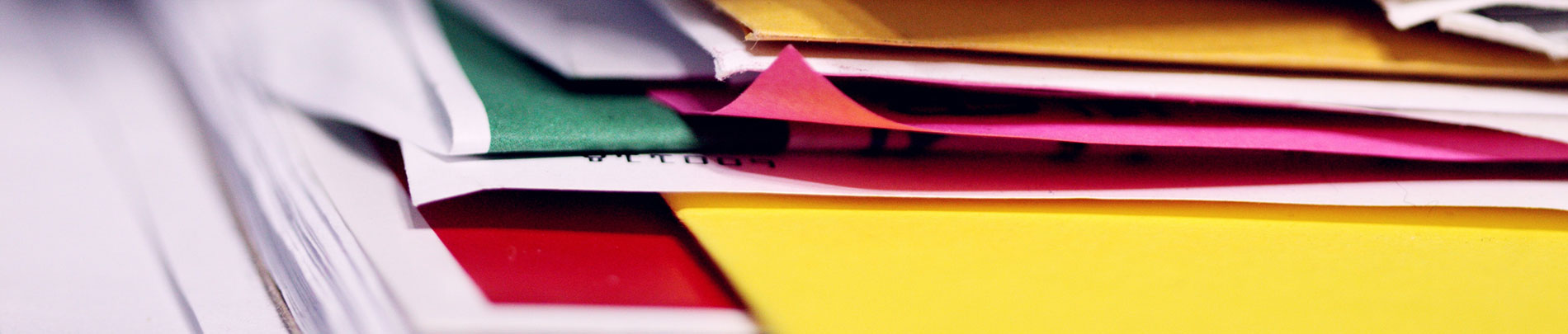 A stack of different coloured papers and reports.