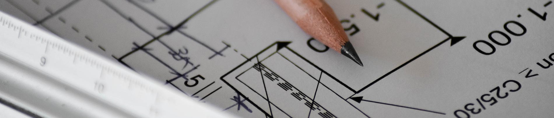 Close up of a pencil and ruler sitting on some building plans.