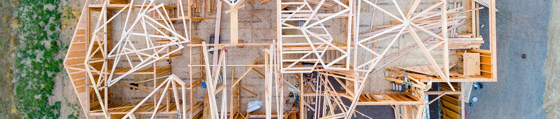 A top down aerial view of a home being built showing the framed walls and rafters.