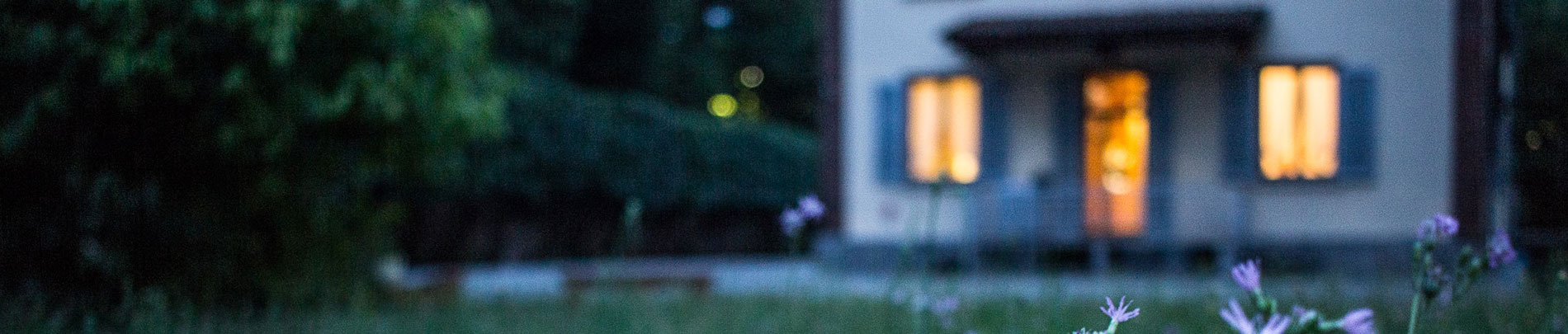 A home lit warmly in the dusk of evening.