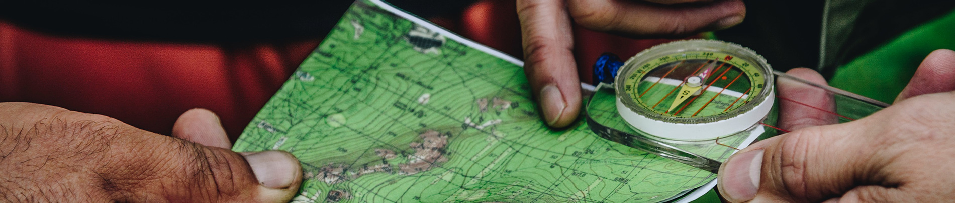 Hands hold a topographic map and compass.