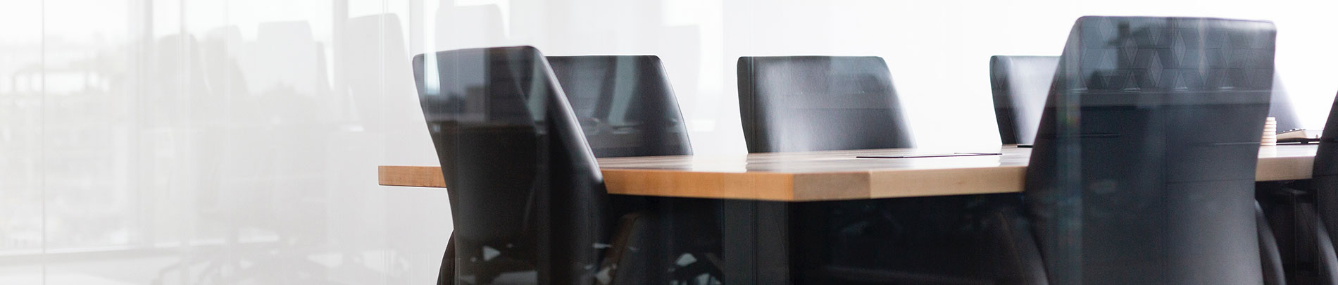 An empty meeting room with black leather chairs at a wooden table.