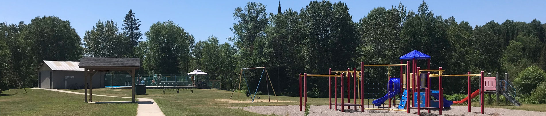 The public park on a sunny day showing the slide and swings.