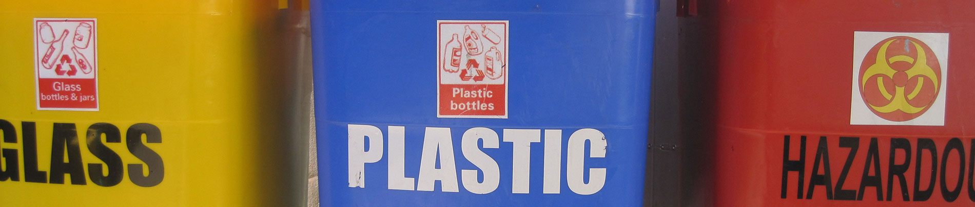 Close up of three colourful recycling bins labelled glass, plastic and hazardous.