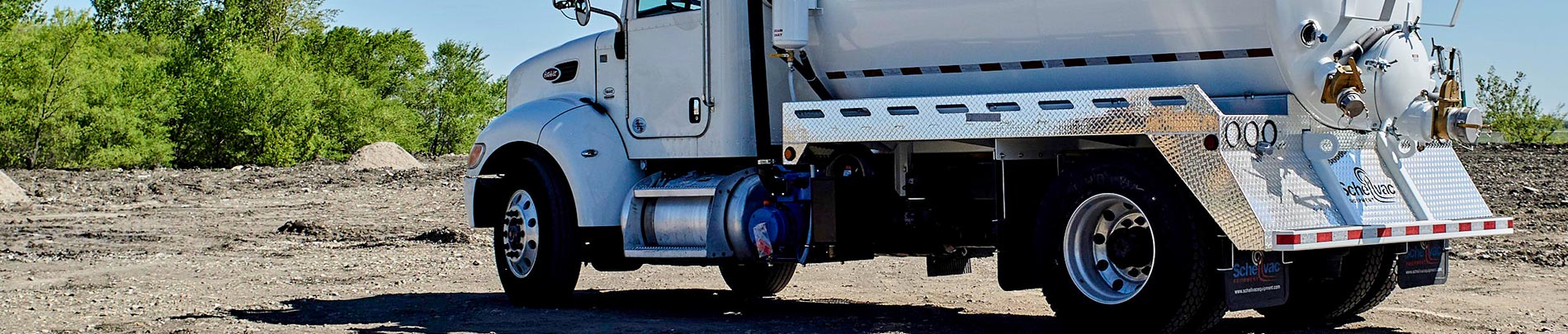 A white septic pumping truck parked at a disposal site.