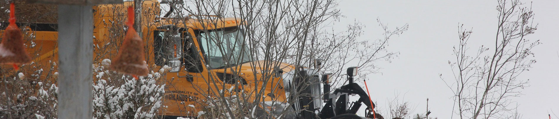 A snowplow clearing a road on a wintery day.