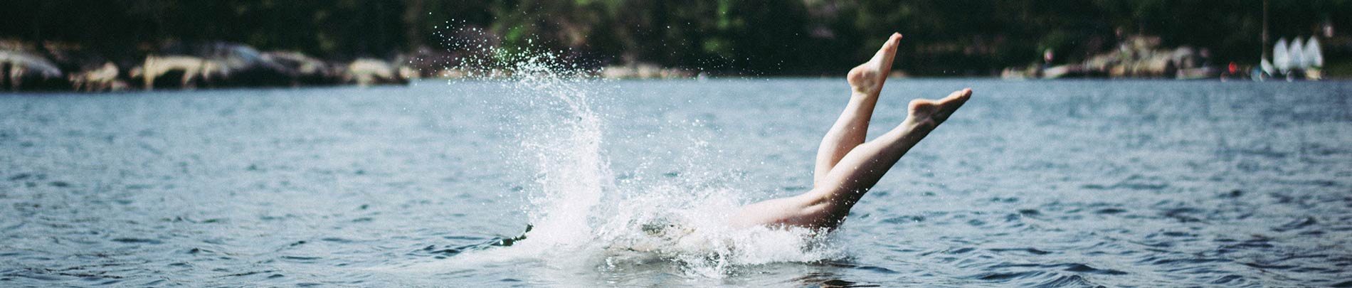 A person's feet splash in the water as they swim in a lake.