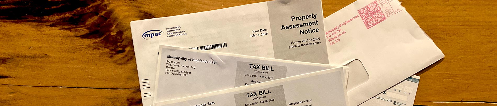 Tax bills and an assessment notice laid out on a wooden desk.