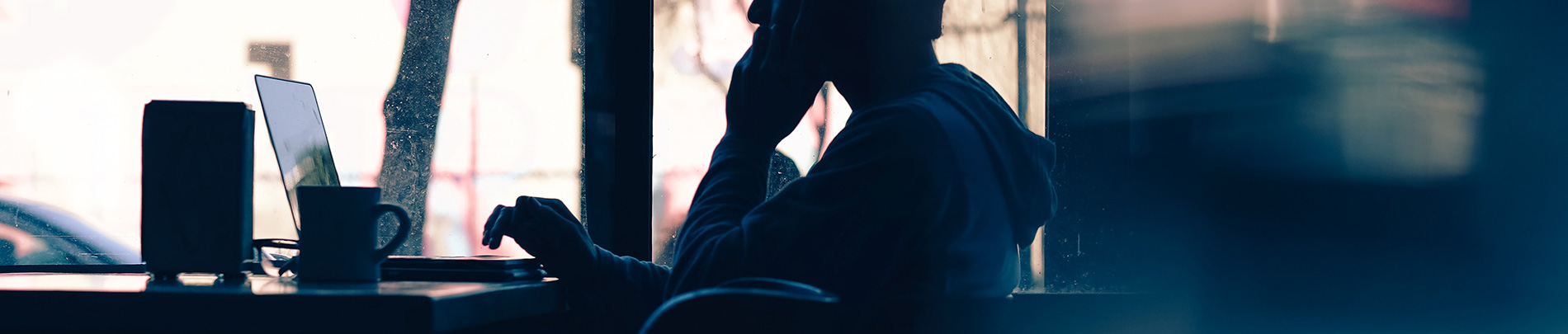 Silhouette of a person using a laptop.