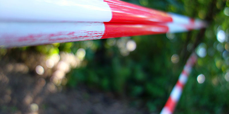 Red and white barricade tape blocking access to an outdoor location.