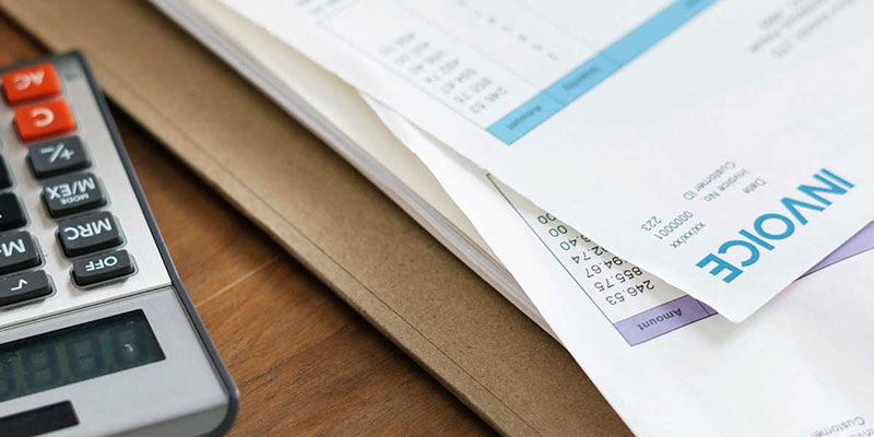 Close up image of a calculator next to an invoice.