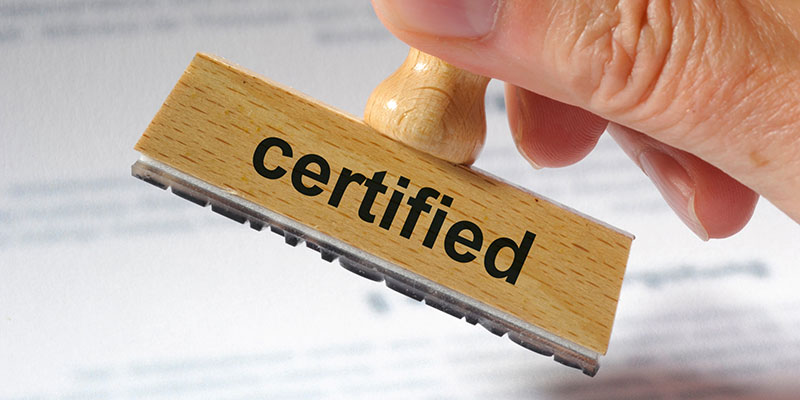 Person stamping papers with a stamp that says Certified.