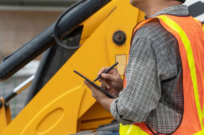 Person in front of backhoe using ipad.