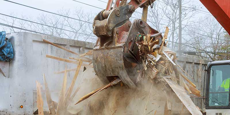 An excavator grabs construction and demolition materials.