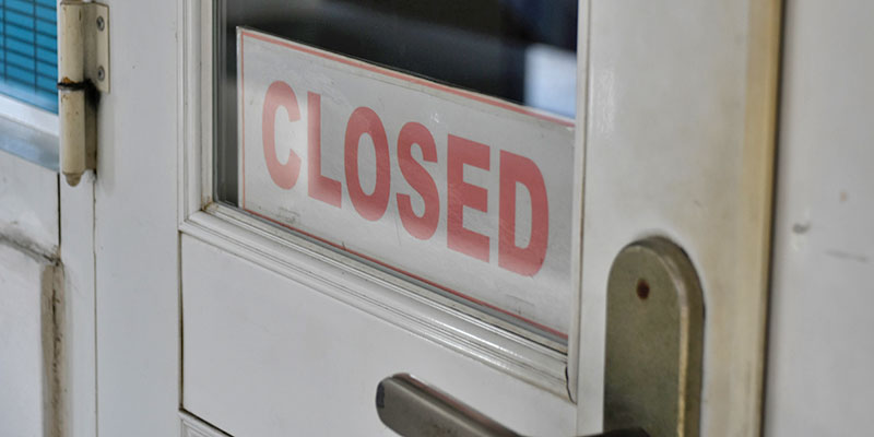 A white door with a red closed sign set in its window.