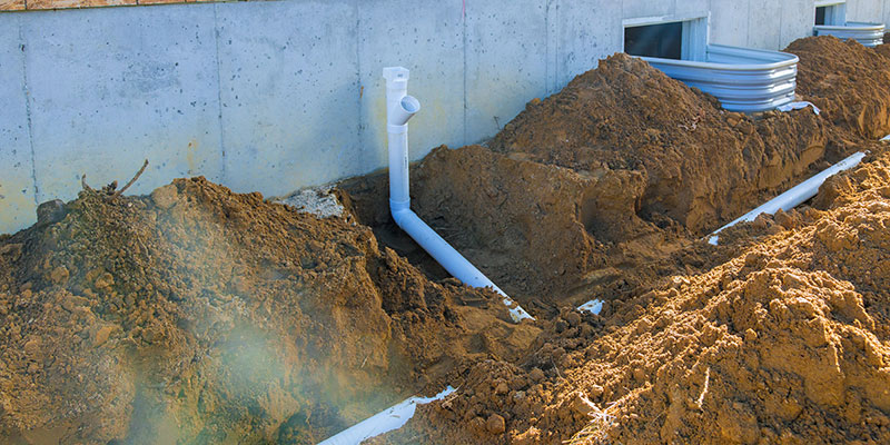 Drainage piping being installed next to a building.