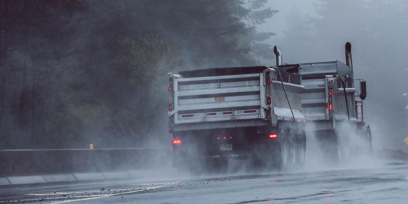 A loaded truck and trailer travelling on a rainy road.