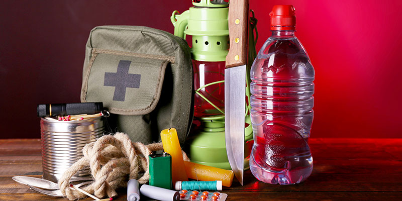 The contents of an emergency kit laid out including a lantern, water, rations, rope and other supplies.