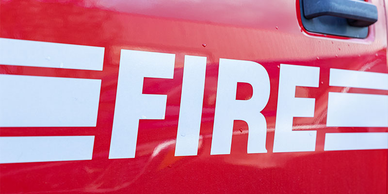Close up of the side of a firetruck with white on red lettering that says FIRE