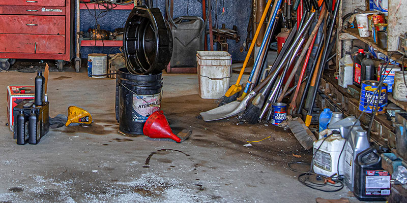 A bunch of old oil cans and paint cans in a garage.