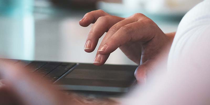 Close up photo of person using a laptop.