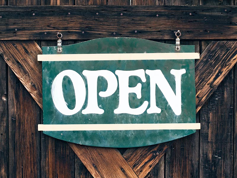 A green open sign hangs on a wooden door.