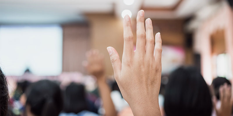 Person raising hand among a bunch of other people.
