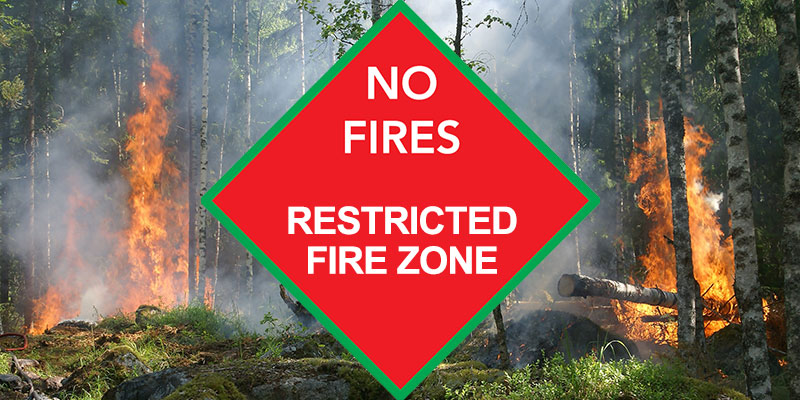 A red diamond sign that reads no fires restricted fire zone superimposed over a photo of a burning forest