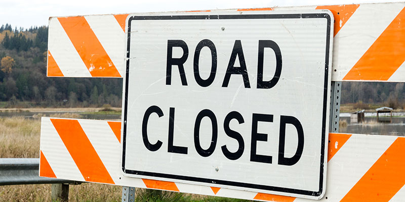 A road closed sign set up on a road.