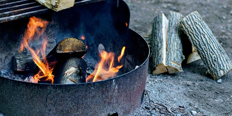 A small campfire burns within an protective metal ring.