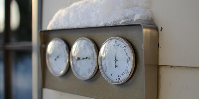 An outdoor thermometer covered in ice and snow.