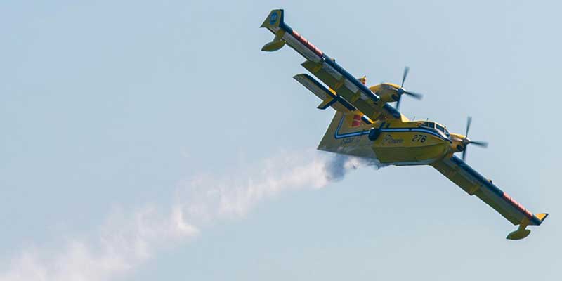 An Ontario Water Bomber flying and dropping water.