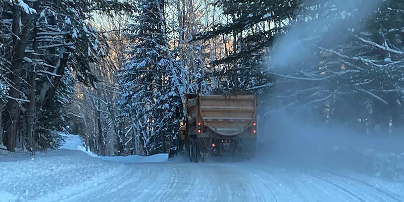 A snow plow clearing a snowy road.